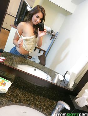Sassy brunette stripping in front of the mirror and making selfies
