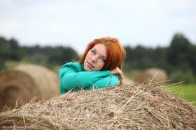 Natural redhead Amber A poses her naked teen body on round bale of hay