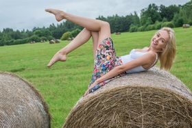 Blonde teen Bernie gets totally naked at a round hay bale in a field