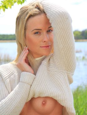 Young blonde Cristal Caitlin lifts up her sweater while bottomless by a river