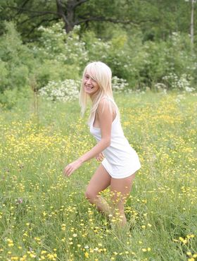 Innocent young blond heads into a field of yellow flowers to pose in the nude