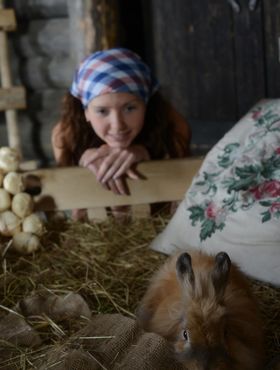 Young brunette girl tends to her farm animals without any clothes on