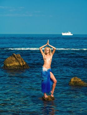 Young blonde girl Aquamarine A goes topless in the ocean amid rocks