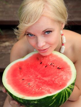Beautiful blonde Feeona eats a watermelon while posing naked on lakeside dock