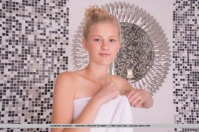 Young looking blonde Lauma removes a bath towel before getting in the bathtub