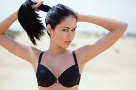 White teen with black hair dresses herself after modeling naked on a beach