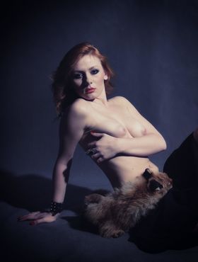 Alluring beauty with red hair puts down a fox and poses in the nude