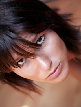 Barefoot girl with brown hair poses her naked body on hardwood flooring