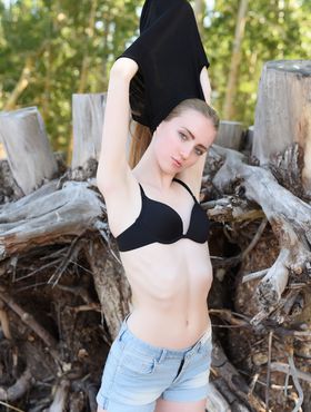 Teen solo girl with long hair Lena Flora gets naked amid driftwood on beach