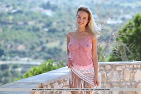 Young blond girl Danica Jewels models nude on a terrace overlooking the valley