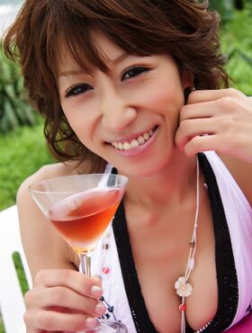 Fun Asian hottie drinks a martini outdoors